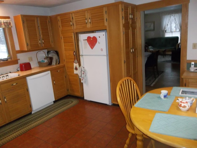 kitchen featuring tasteful backsplash, brown cabinetry, white appliances, and light countertops