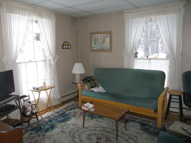 living area with plenty of natural light, a paneled ceiling, and a baseboard radiator