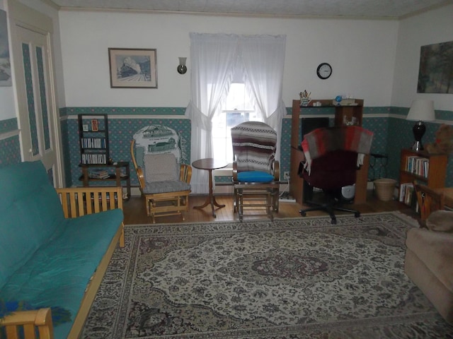 living area with wood finished floors and wallpapered walls