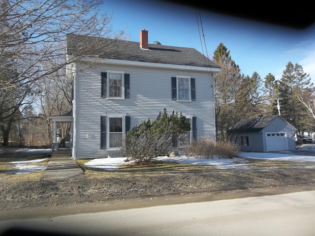 colonial inspired home featuring an outbuilding, a detached garage, and a chimney