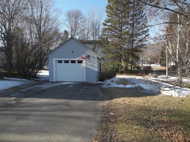 snow covered garage featuring aphalt driveway and a detached garage