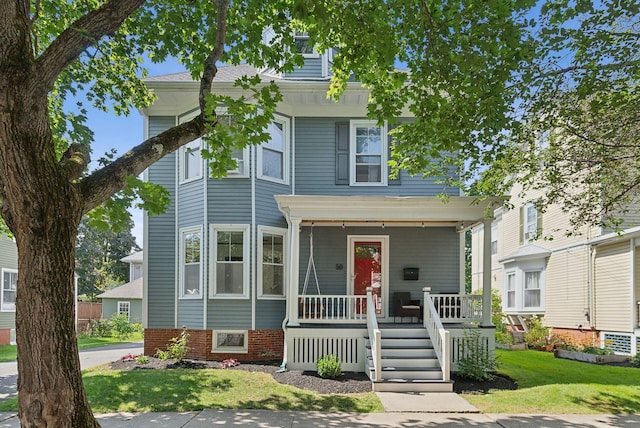 view of front of home featuring a front lawn, brick siding, and covered porch