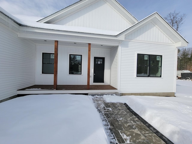 snow covered property entrance with covered porch