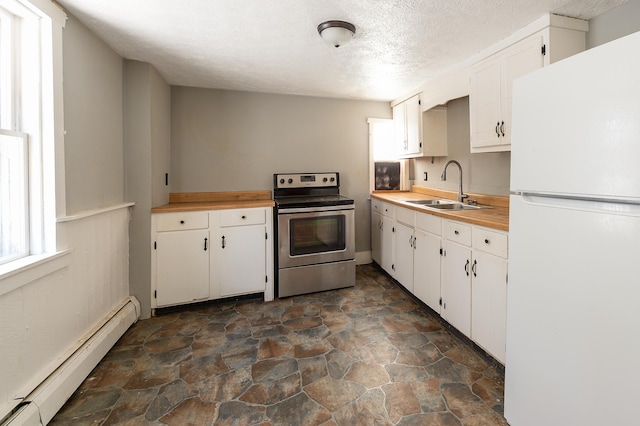 kitchen featuring stainless steel electric stove, white cabinetry, sink, white fridge, and baseboard heating