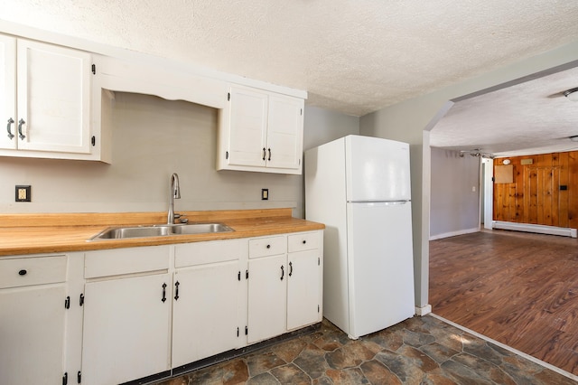 kitchen featuring sink, white refrigerator, white cabinets, a textured ceiling, and a baseboard radiator