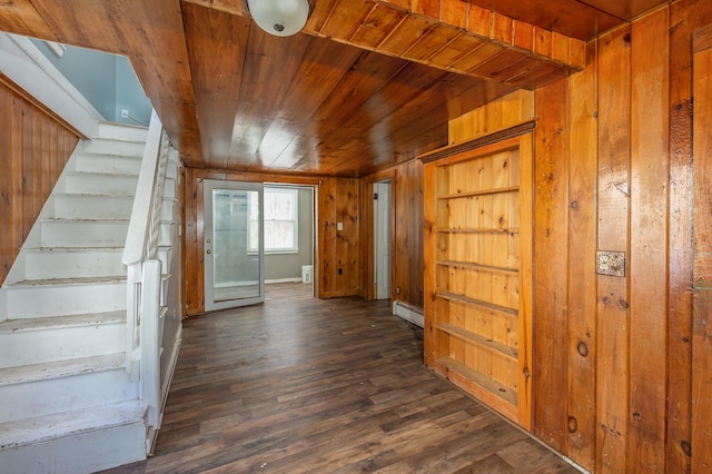 interior space with dark wood-type flooring, wood ceiling, baseboard heating, and wood walls