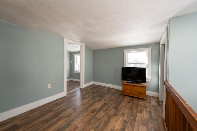 unfurnished living room featuring dark hardwood / wood-style flooring, vaulted ceiling, and a textured ceiling