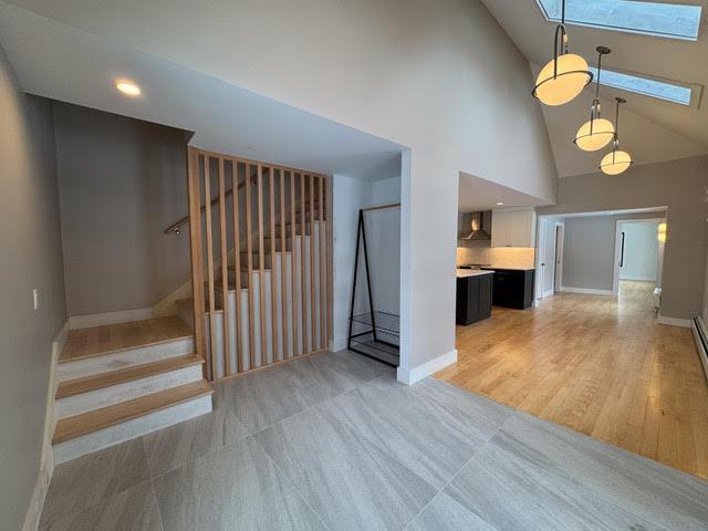 interior space with light hardwood / wood-style flooring, a skylight, and high vaulted ceiling