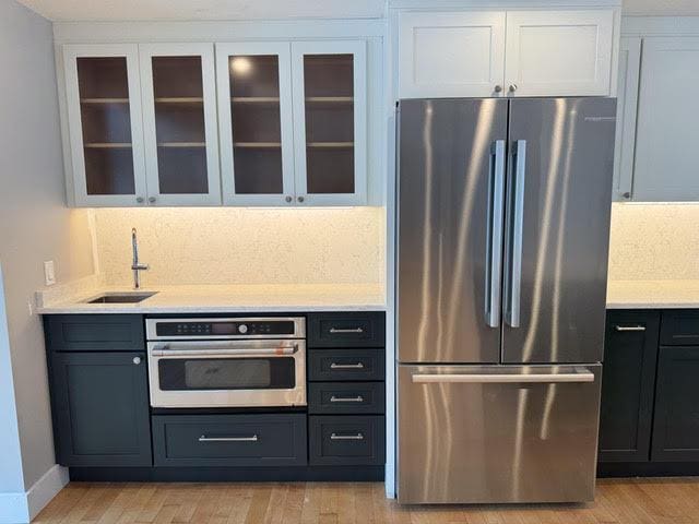 kitchen with white cabinetry, stainless steel appliances, sink, and light wood-type flooring