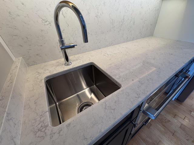 interior details featuring hardwood / wood-style flooring, light stone countertops, and sink