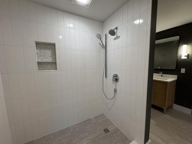 bathroom with vanity, hardwood / wood-style floors, and tiled shower