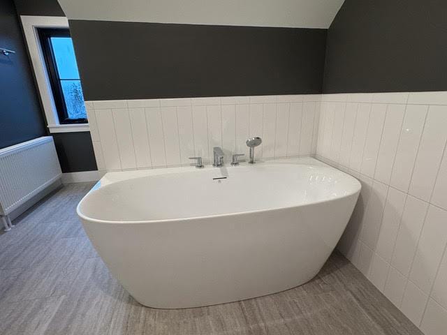 bathroom with radiator heating unit and a tub to relax in