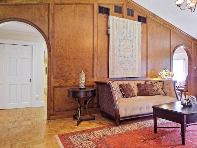 living room with light parquet floors, ornamental molding, and wood walls