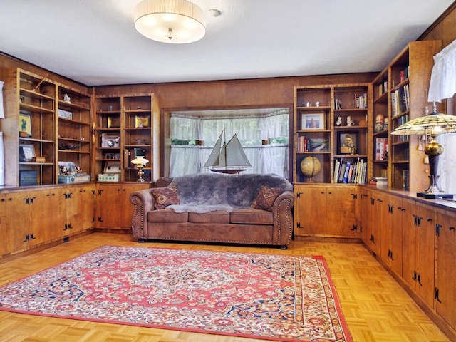 living room with light parquet floors and wood walls