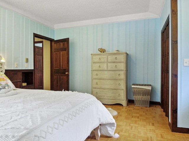 bedroom with wood walls, a textured ceiling, and light parquet floors