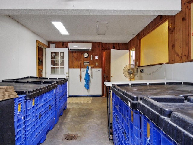 kitchen with wooden walls, a wall unit AC, white refrigerator, blue cabinetry, and a textured ceiling