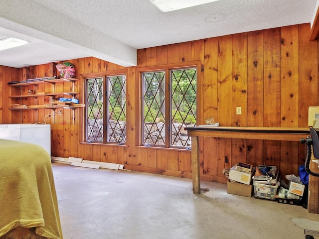 bedroom with a textured ceiling, concrete floors, and wood walls