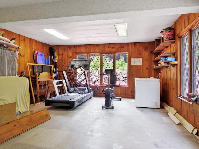 exercise room with a textured ceiling and wood walls