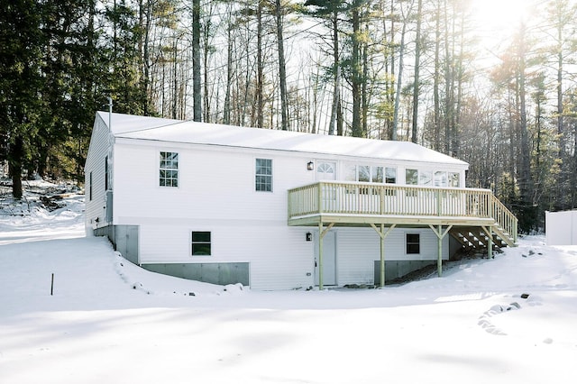 snow covered front of house featuring a wooden deck