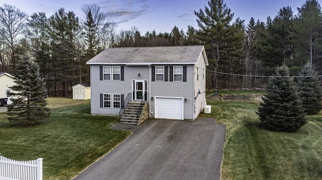 split foyer home featuring a garage, a storage unit, and a front lawn