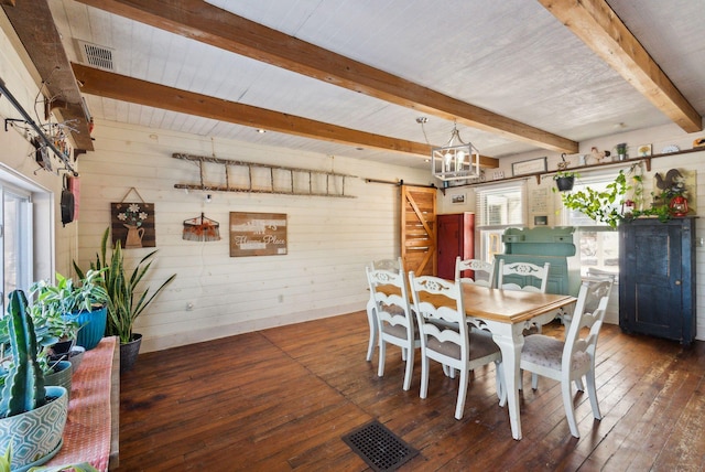 dining space with dark hardwood / wood-style flooring, wooden walls, a barn door, and beam ceiling