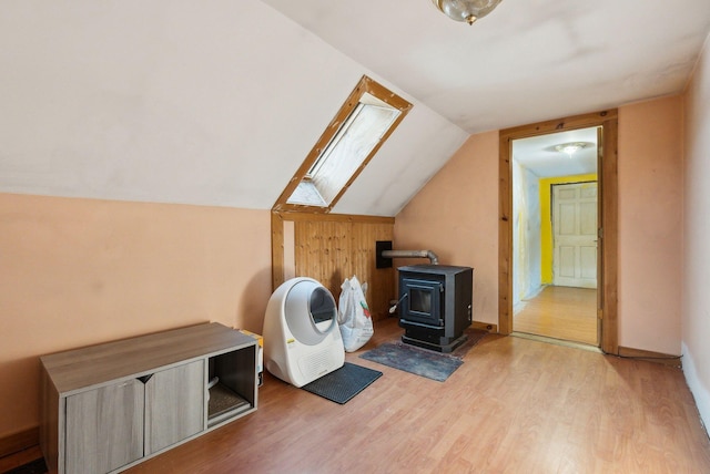 laundry area with light wood-type flooring, a wood stove, and a skylight