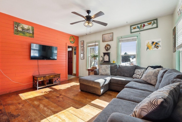 living room with ceiling fan, wooden walls, and light hardwood / wood-style floors