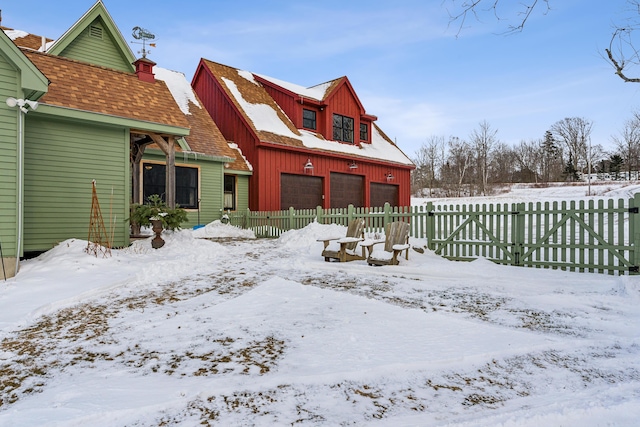 snow covered rear of property with a garage