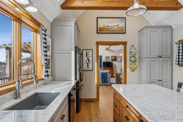 kitchen featuring sink, light hardwood / wood-style flooring, hanging light fixtures, lofted ceiling with beams, and light stone countertops