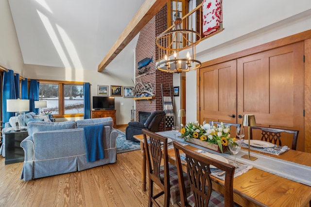 dining space featuring lofted ceiling, a fireplace, light wood-type flooring, and a notable chandelier