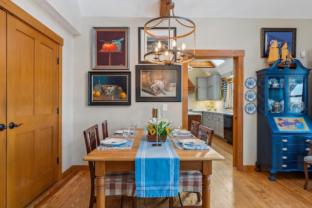 dining room featuring lofted ceiling, a chandelier, and light hardwood / wood-style floors