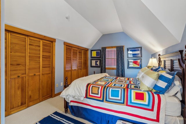 carpeted bedroom with lofted ceiling and two closets