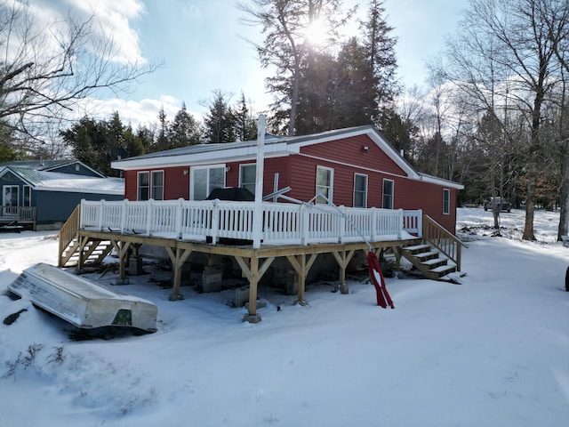 snow covered back of property featuring a deck