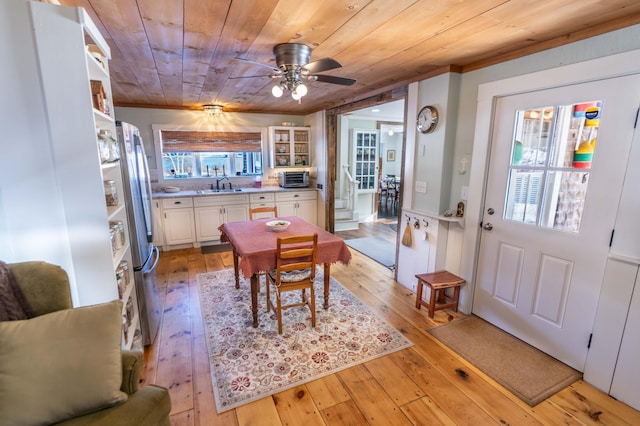 dining area featuring a healthy amount of sunlight, sink, wood ceiling, and light hardwood / wood-style floors