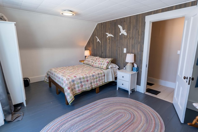 bedroom with dark hardwood / wood-style flooring, wooden walls, and vaulted ceiling