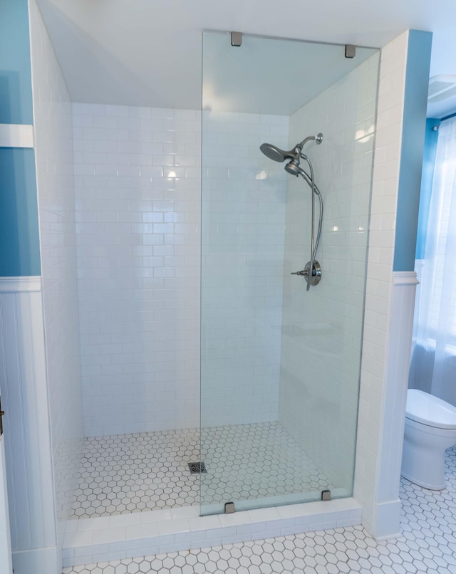 bathroom with tile patterned flooring, toilet, and tiled shower