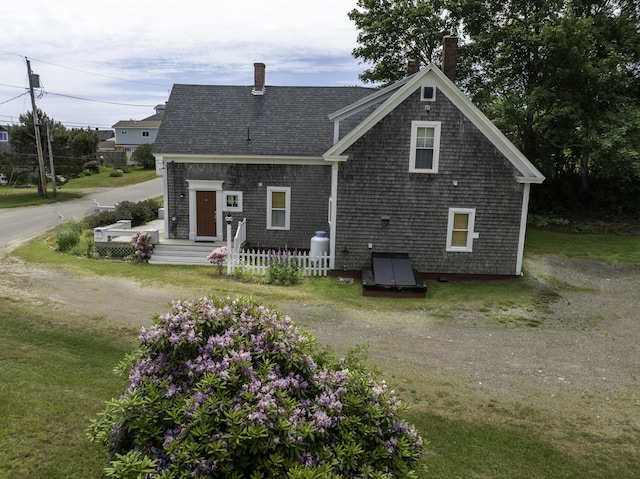 194 Water St, Eastport, ME 04631 - rear view of property featuring a chimney, a shingled roof, and driveway