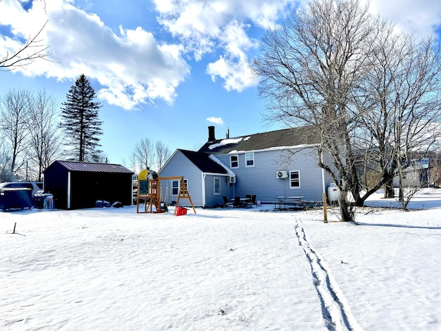 snow covered rear of property with a playground