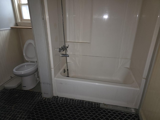 bathroom featuring wooden walls, toilet, and bathing tub / shower combination