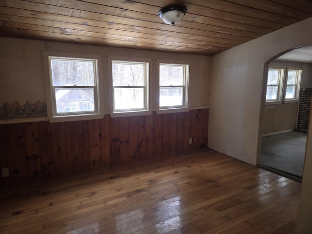 empty room featuring wood ceiling, dark wood-type flooring, and wood walls