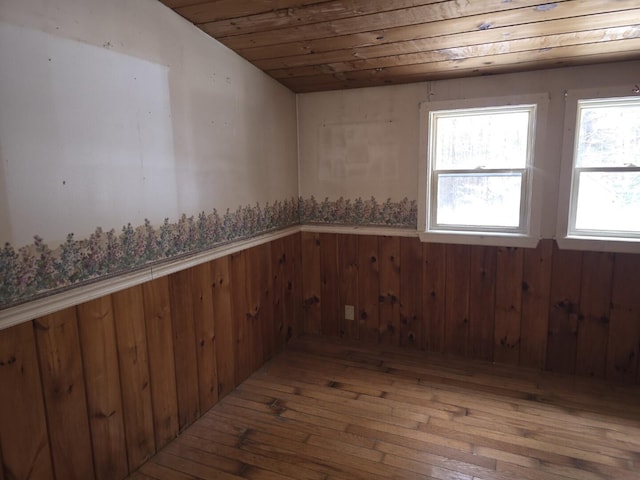 empty room with hardwood / wood-style flooring, wooden ceiling, and wood walls