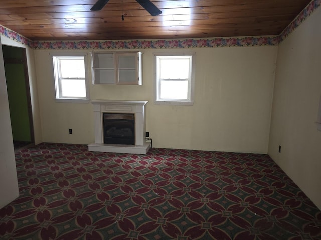 unfurnished living room with a healthy amount of sunlight, wooden ceiling, and ceiling fan