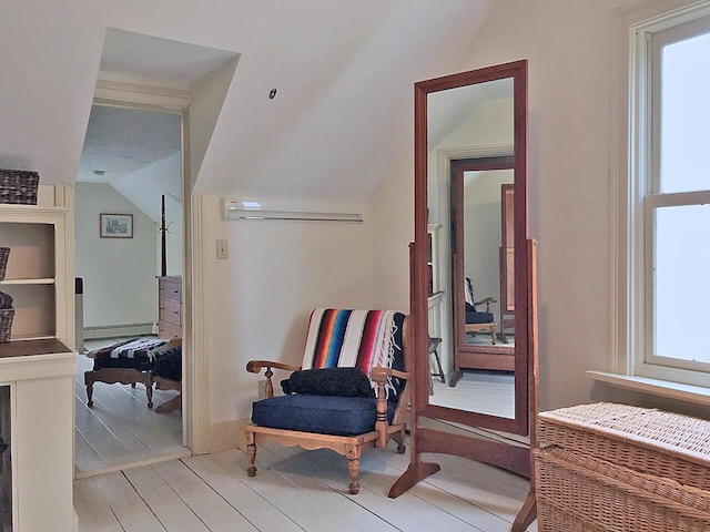 hallway featuring vaulted ceiling, a wall unit AC, light wood-type flooring, a wall mounted air conditioner, and a baseboard heating unit