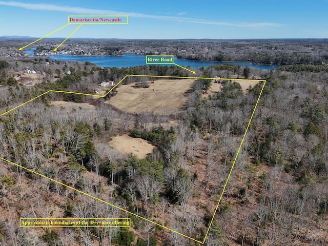 drone / aerial view featuring a water view and a wooded view