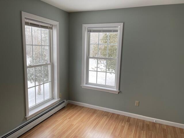 unfurnished room featuring a baseboard radiator, baseboards, and light wood-style flooring