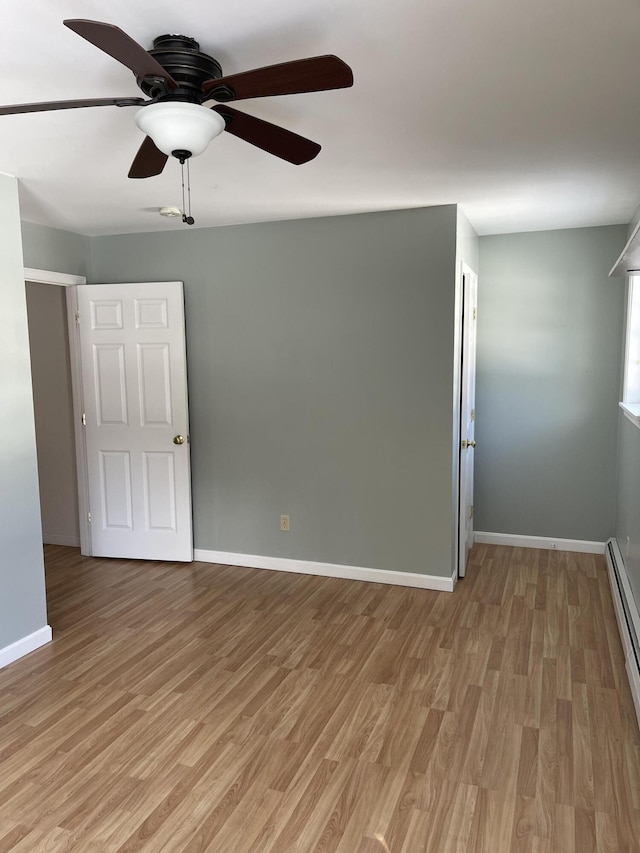 empty room with a baseboard radiator, light wood-style flooring, and baseboards