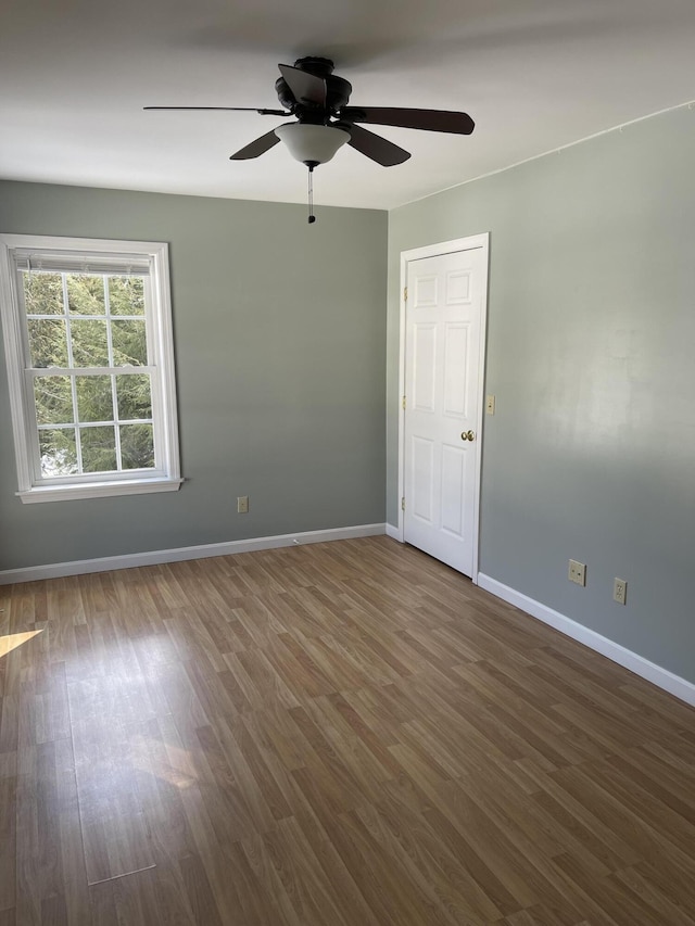 spare room with ceiling fan, baseboards, and dark wood-type flooring