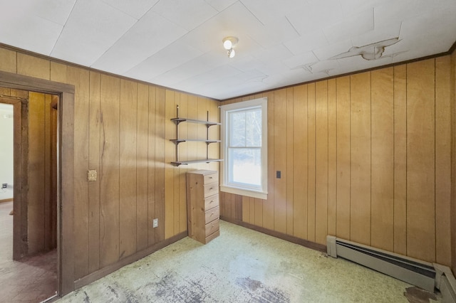 spare room with a baseboard heating unit and wooden walls