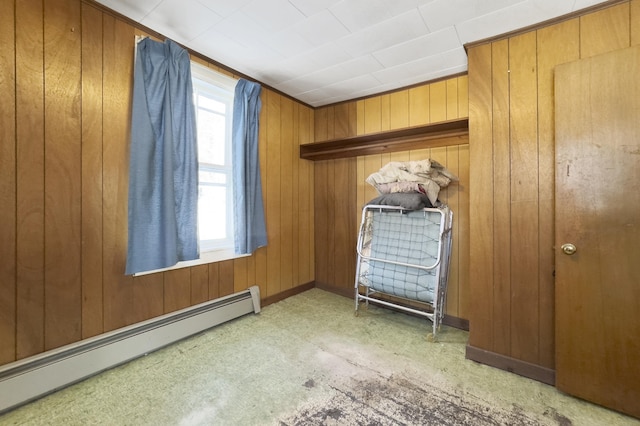 unfurnished bedroom featuring wooden walls and baseboard heating