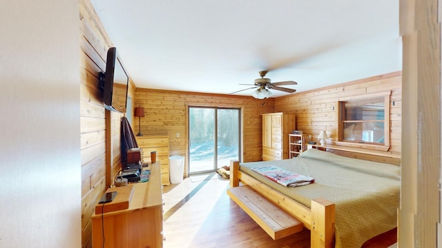 bedroom featuring hardwood / wood-style flooring, access to outside, wooden walls, and ceiling fan